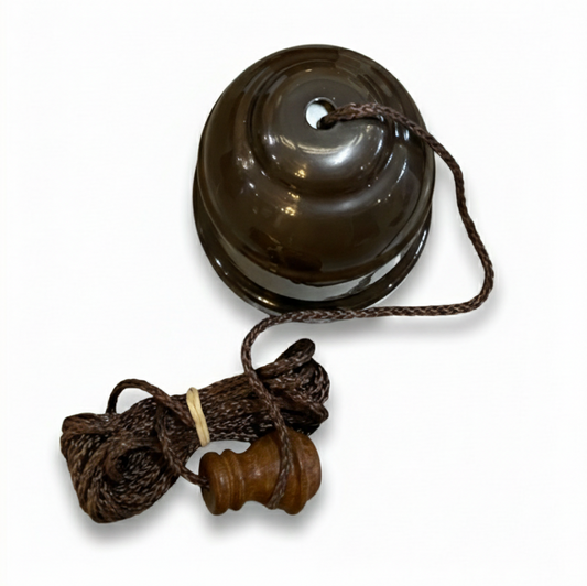 Bronze ceiling pull cord switch with a smooth, polished bronze base and a long, woven brown fabric cord hanging vertically beneath it, set against a plain white background.