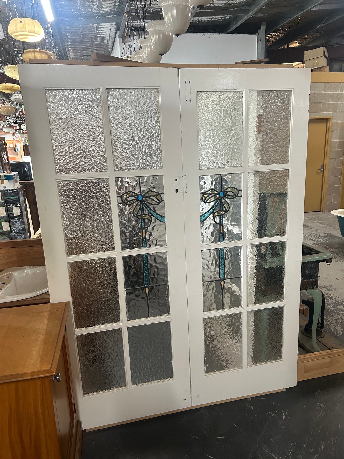 An original salvaged Federation style timber door painted white, showcasing an upper vertical three-panel window layout with elegant purple and green leadlight privacy glass on display at Chippendale Restorations.