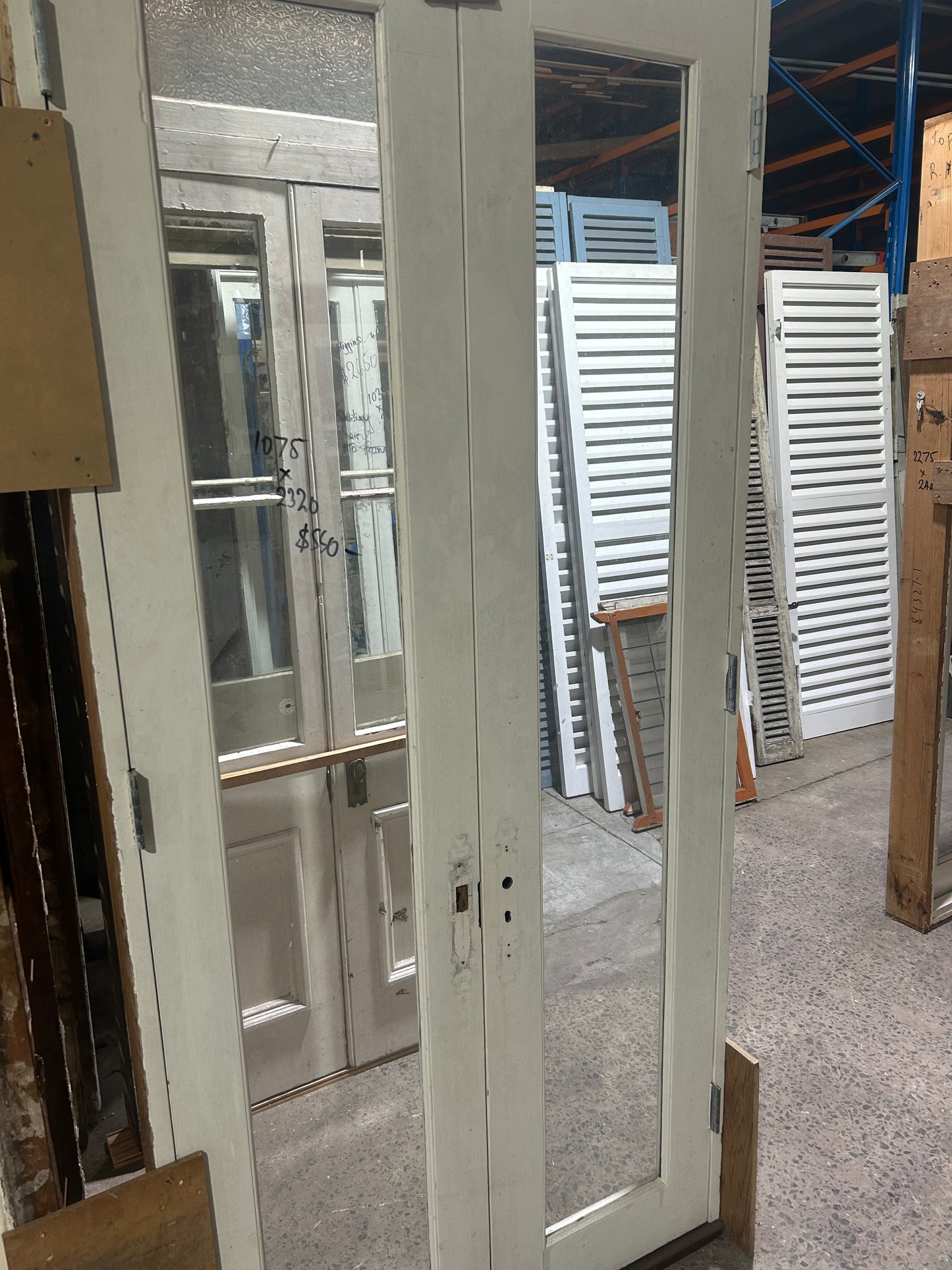 An original salvaged California Bungalow style internal timber door painted white, featuring five horizontal recessed panels on display at Chippendale Restorations.