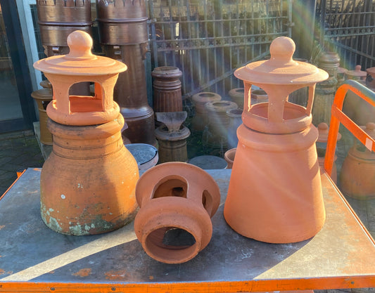 Three terracotta chimney pots, two tall with domed cowls for roof ventilation, one shorter cowl sitting in front. New in Sydney