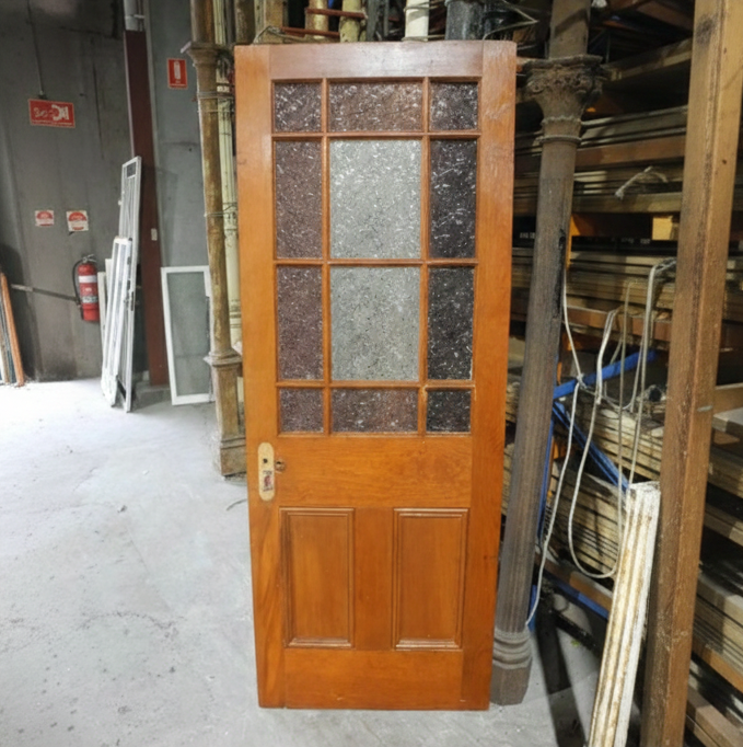 An original salvaged timber Federation gallery door painted white, showcasing an upper window with multi-lite red and amber glass framing a rare central pane of pressed flannel flower privacy glass at Chippendale Restorations.
