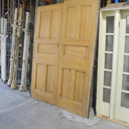 A matching pair of original salvaged Federation timber sliding doors painted white, featuring a multi-lite clear glass window design on the upper half, inside the Chippendale Restorations showroom.