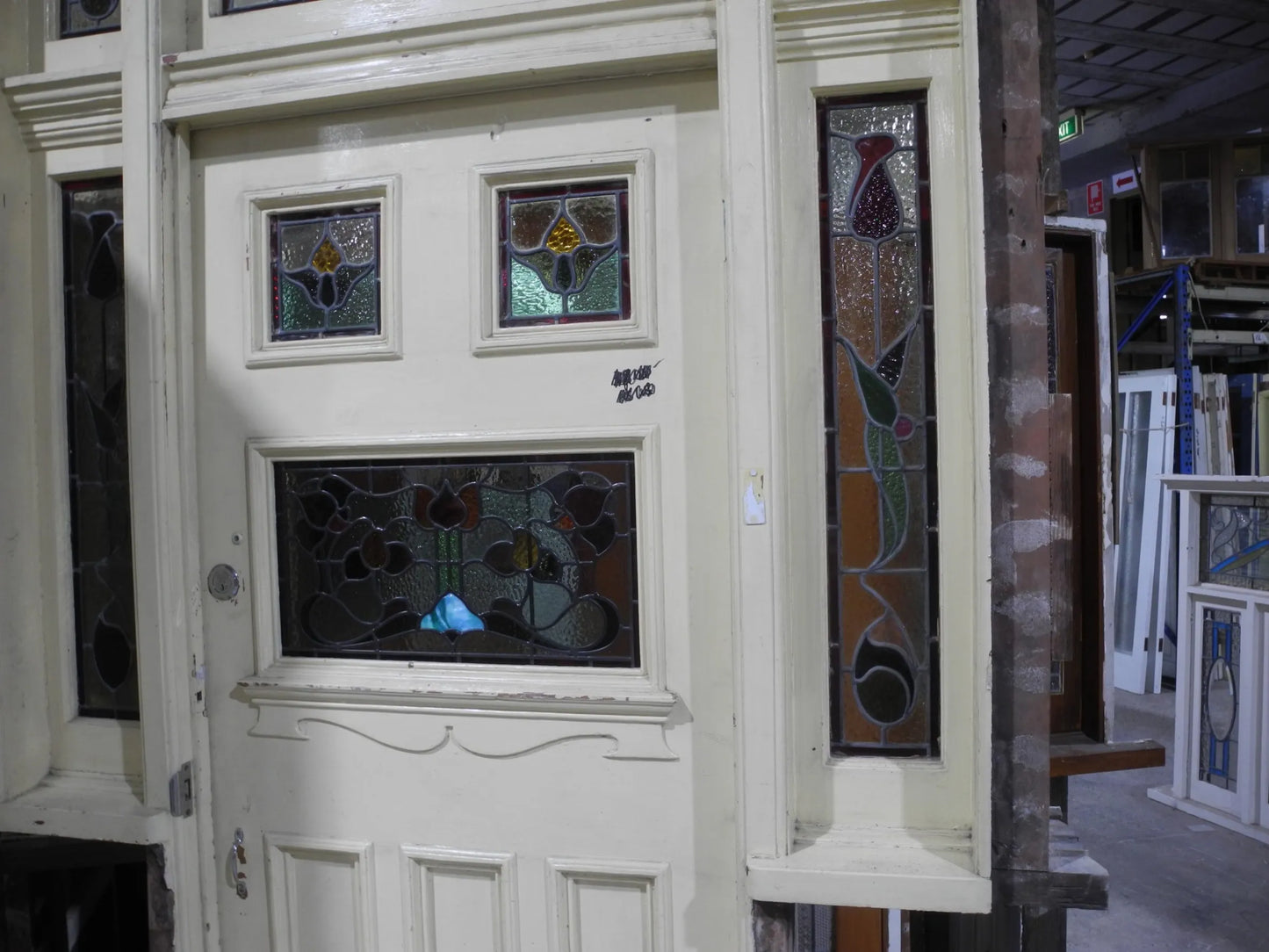A spectacular original salvaged timber Federation entranceway door painted white, showcasing a large upper window with intricate textured privacy leadlight glass and vibrant red and amber stained glass accents on display at Chippendale Restorations.