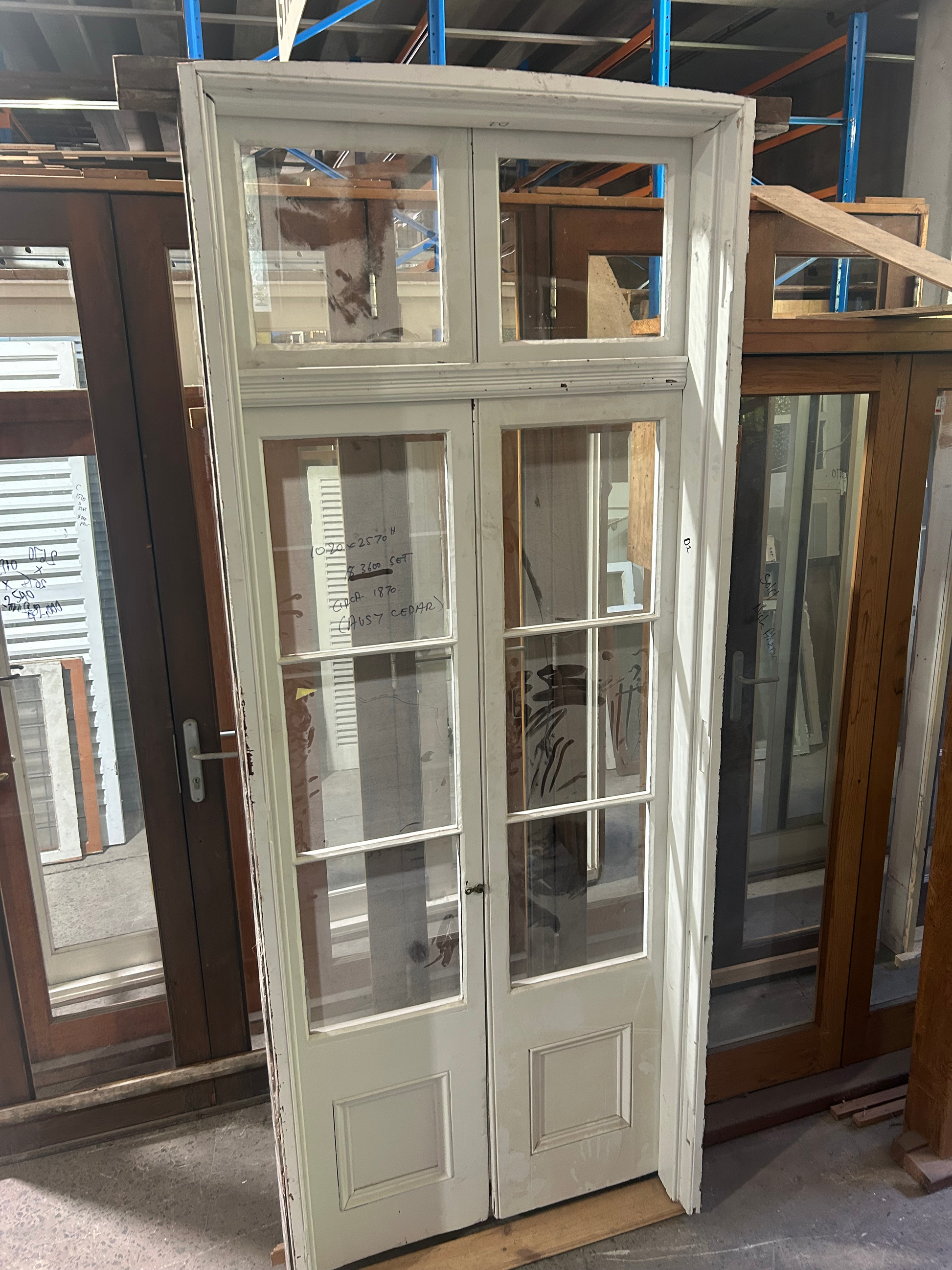 Stately pair of tall Victorian timber French doors circa 1870 featuring clear glass upper window panes and deep solid lower panels, from Chippendale Restorations second hand doors selection.
