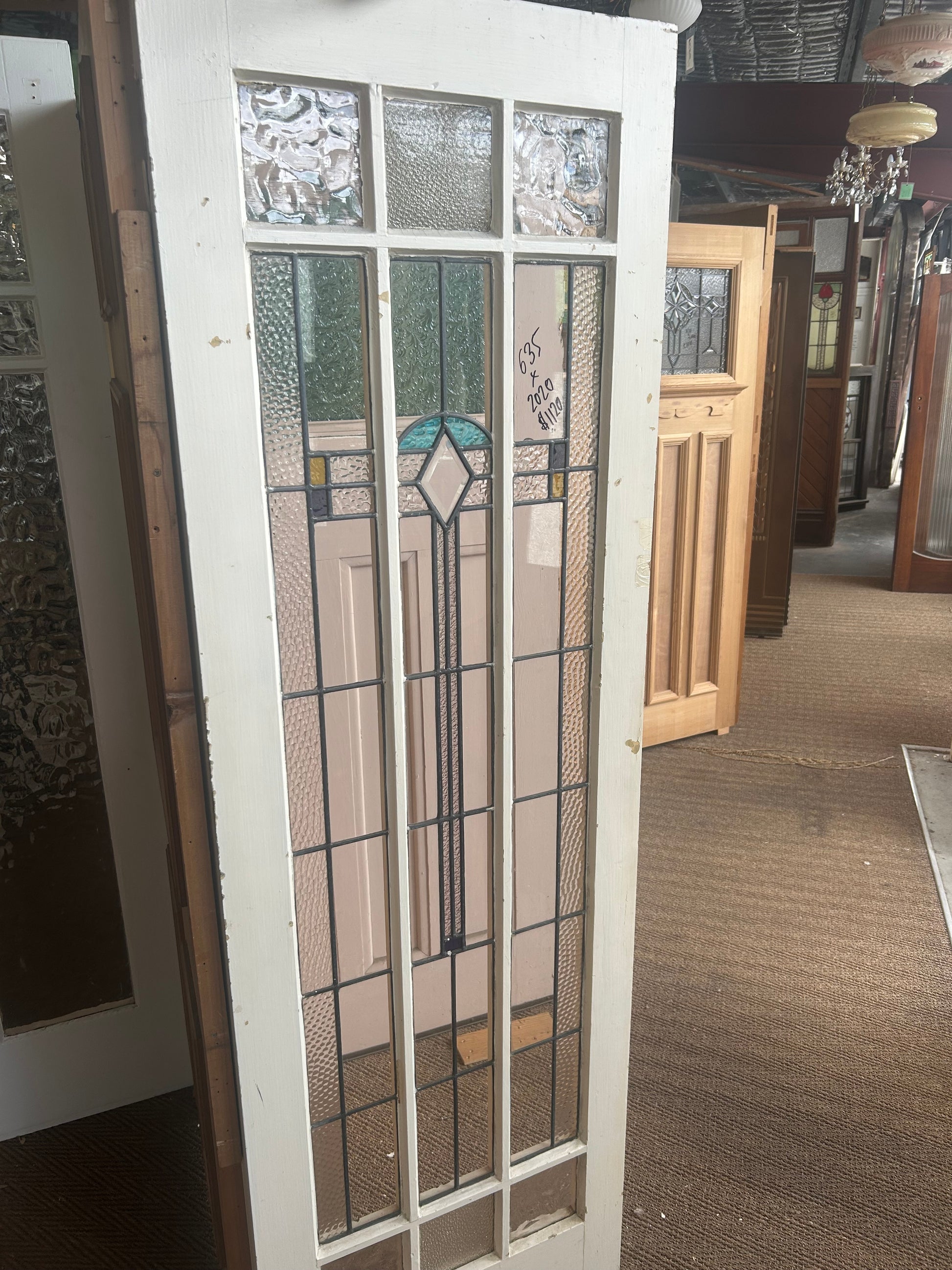 Vintage white timber Federation leadlight door with a detailed geometric stained glass panel, displayed inside the Chippendale Restorations architectural salvage showroom.
