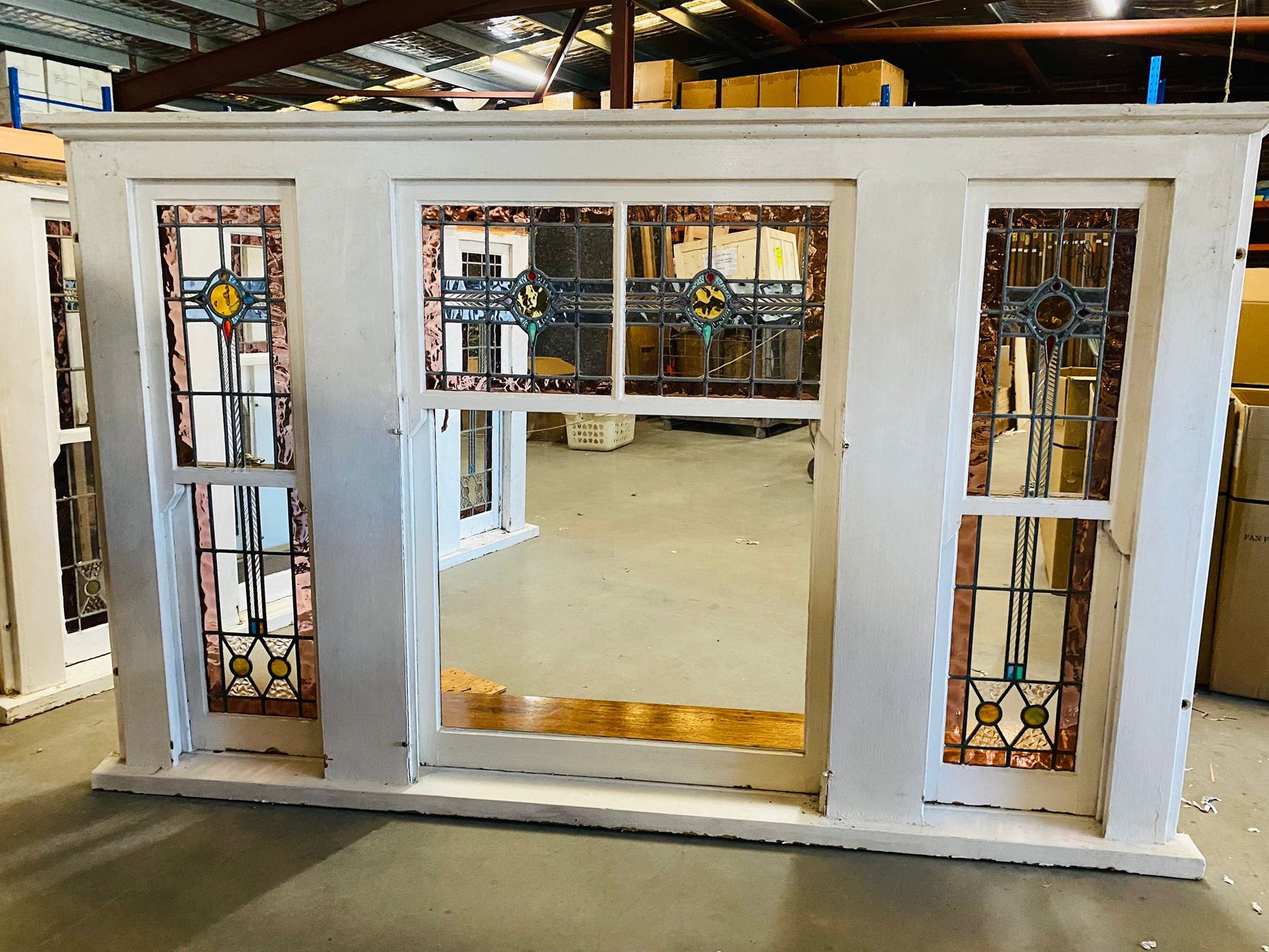 A set of original salvaged triple double-hung timber windows painted green on the exterior frame, showcasing classic multi-pane glass panels on display at Chippendale Restorations.