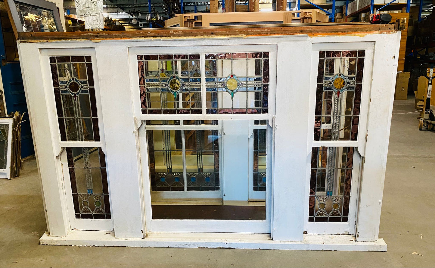 A set of original salvaged triple double-hung timber windows painted green on the exterior frame, showcasing classic multi-pane glass panels on display at Chippendale Restorations.
