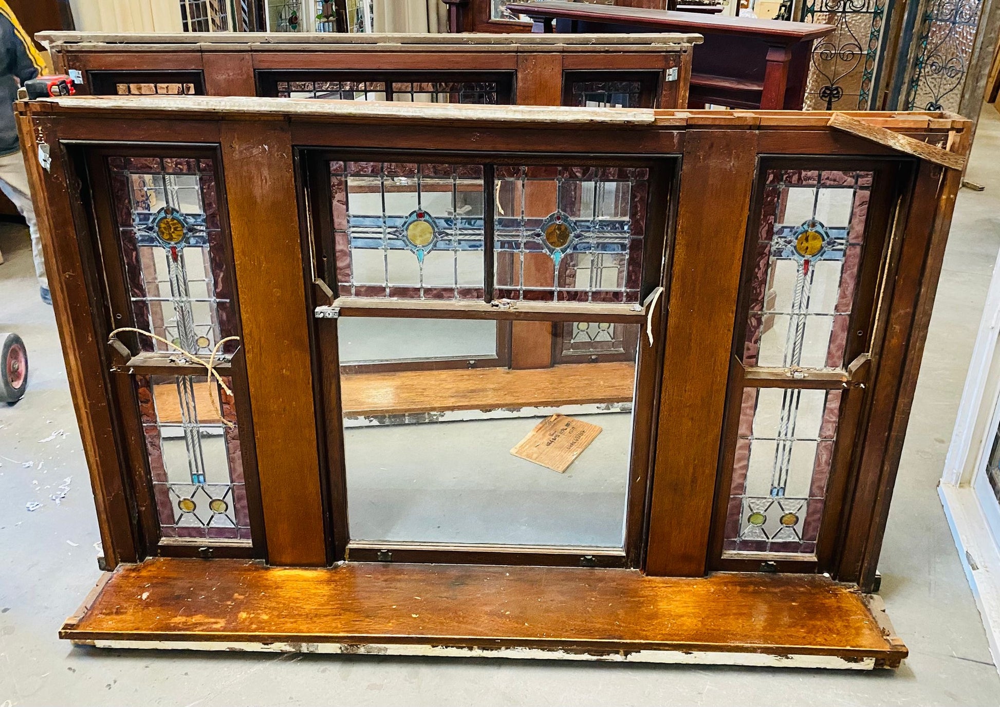 A set of original salvaged triple double-hung timber windows painted green on the exterior frame, showcasing classic multi-pane glass panels on display at Chippendale Restorations.