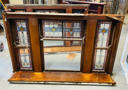 A set of original salvaged triple double-hung timber windows painted green on the exterior frame, showcasing classic multi-pane glass panels on display at Chippendale Restorations.
