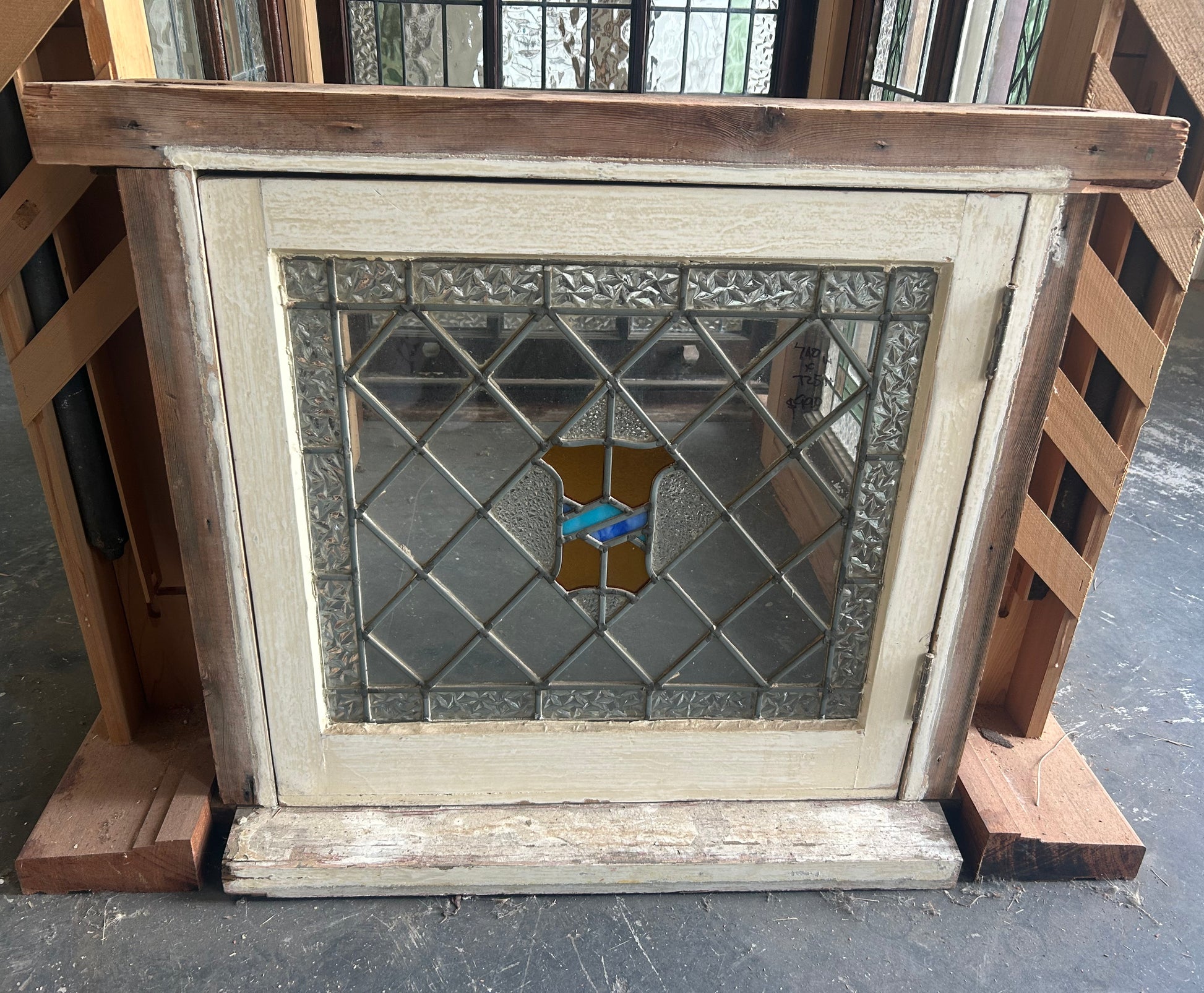 An original salvaged antique leadlight window set in a dark timber frame, featuring textured clear privacy glass with vibrant green and amber geometric borders at Chippendale Restorations.