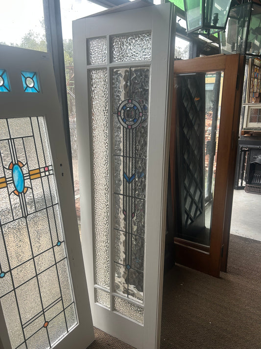 An original salvaged Federation style timber entry door painted white, featuring an upper leadlight glass window panel with textured glass and stained glass accents on display at Chippendale Restorations.