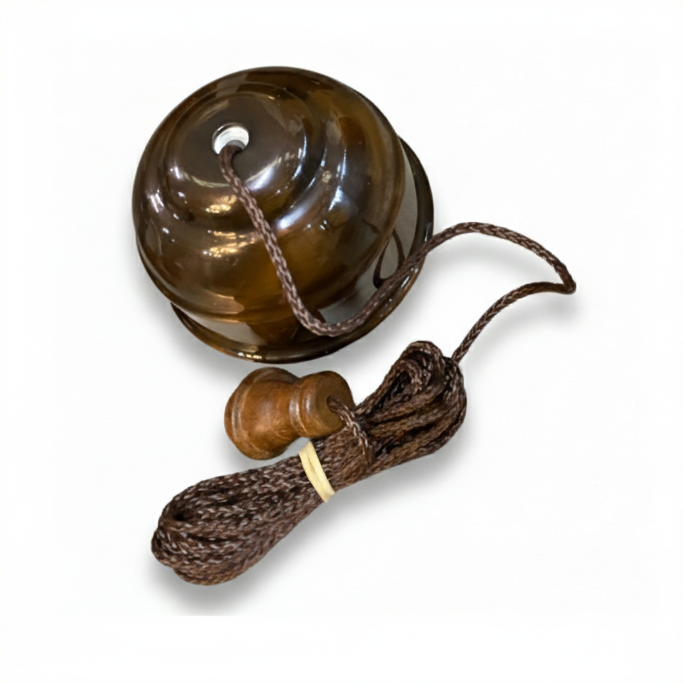 Bronze ceiling pull cord switch with a smooth, polished bronze base and a long, woven brown fabric cord hanging vertically beneath it, set against a plain white background.