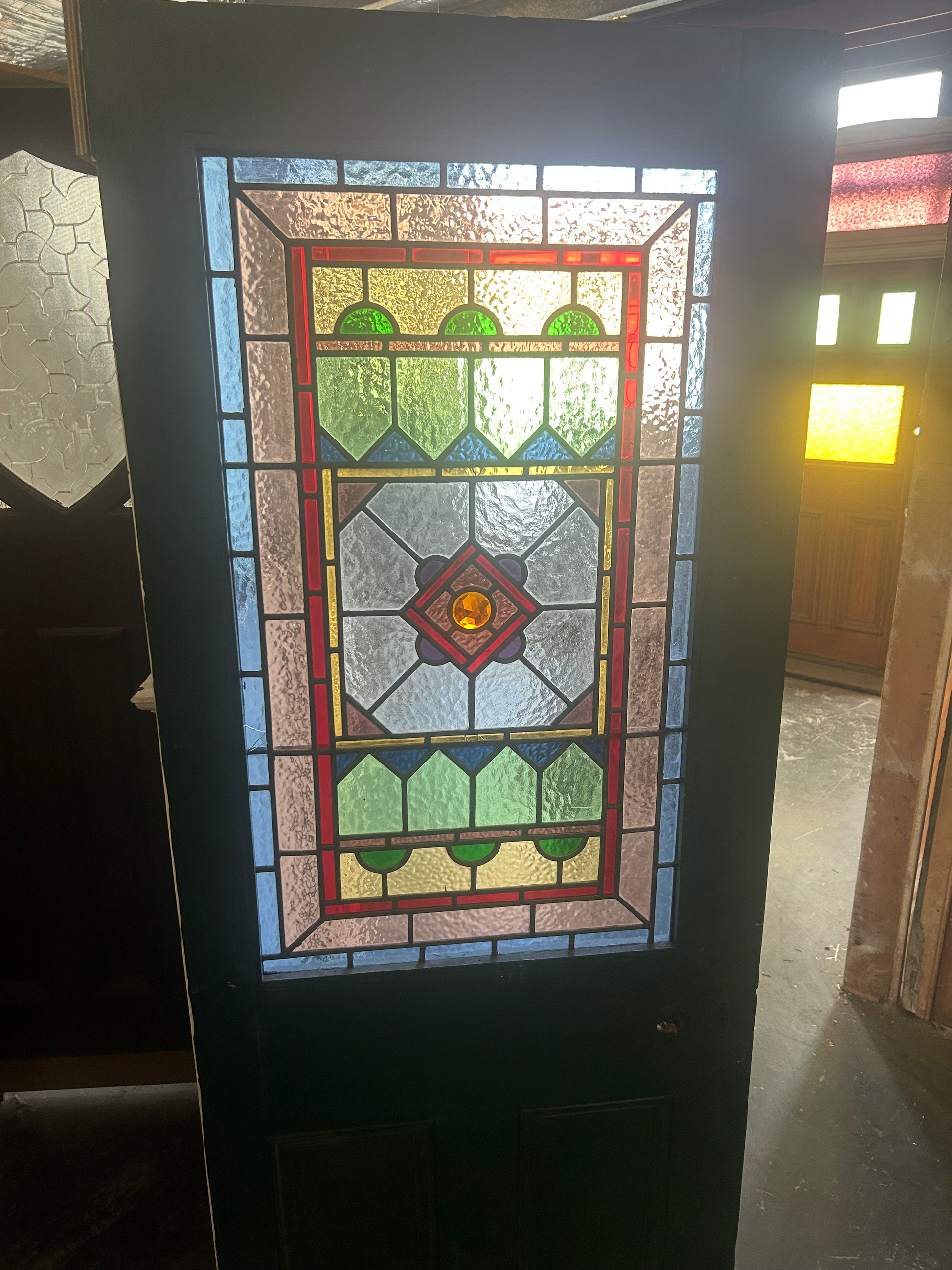 Antique Victorian leadlight front door painted deep green featuring a large geometric stained glass panel at Chippendale Restorations second hand doors warehouse.