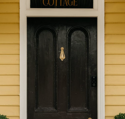 Traditional teardrop-shaped Edwardian door knocker hardware mounted on a front door, showcasing elegant heritage style for period home entryways.