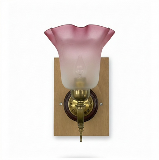 Vintage brass wall sconce with a decorative arm, a polished wood roundel and square backplate, and a red and frosted clear fluted glass lampshade.