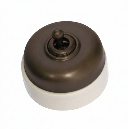 Porcelain-based electrical switch with a visible metal dolly. Available in a polished brass or antique brass finish on either a white porcelain base or a black porcelain base.