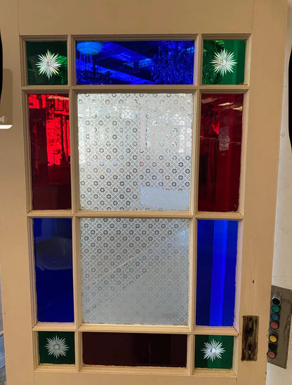 An original salvaged Victorian timber gallery door featuring multi-lite red, blue, and patterned privacy glass windows with four green starburst brilliant-cut corners on display at Chippendale Restorations.