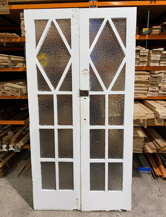 A pair of original salvaged 1920s timber French doors with multi-pane glazing and prominent central amber diamond leadlight windows, on display at Chippendale Restorations.