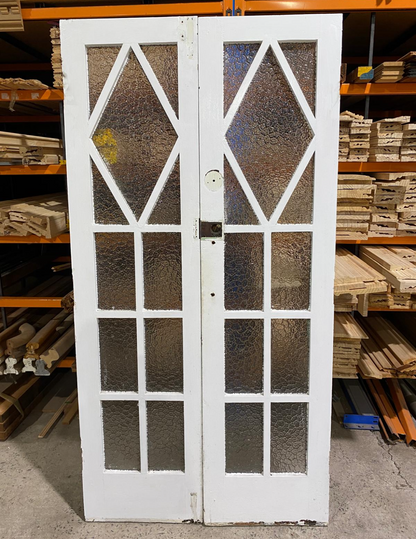 A pair of original salvaged 1920s timber French doors with multi-pane glazing and prominent central amber diamond leadlight windows, on display at Chippendale Restorations.