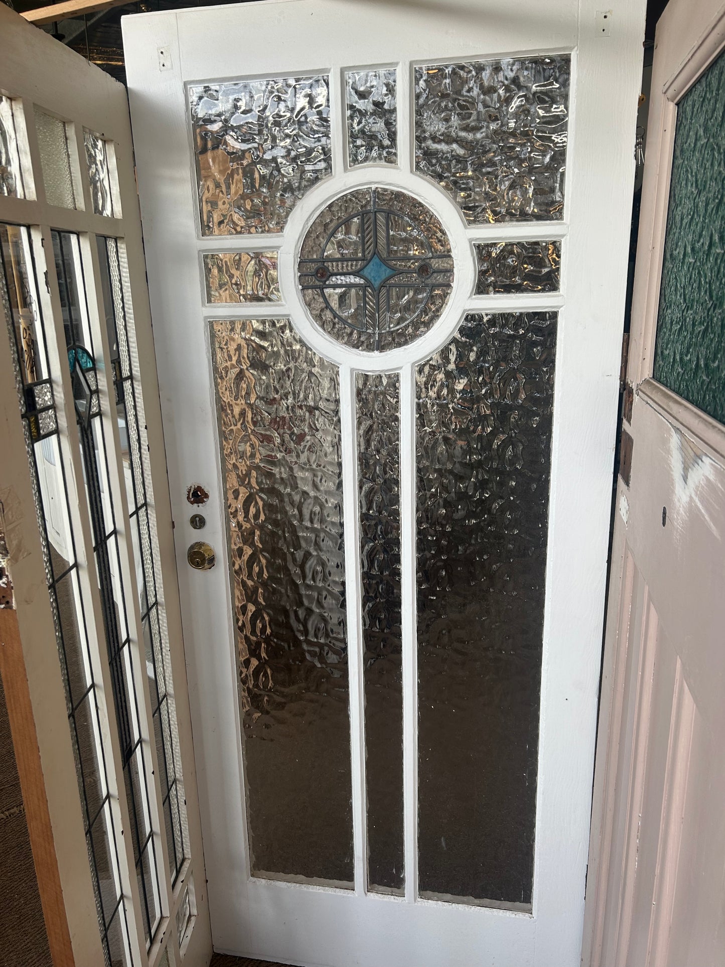 An original salvaged Federation style timber door painted white, featuring an upper window panel with textured privacy glass and a red and green leadlight floral design on display at Chippendale Restorations.