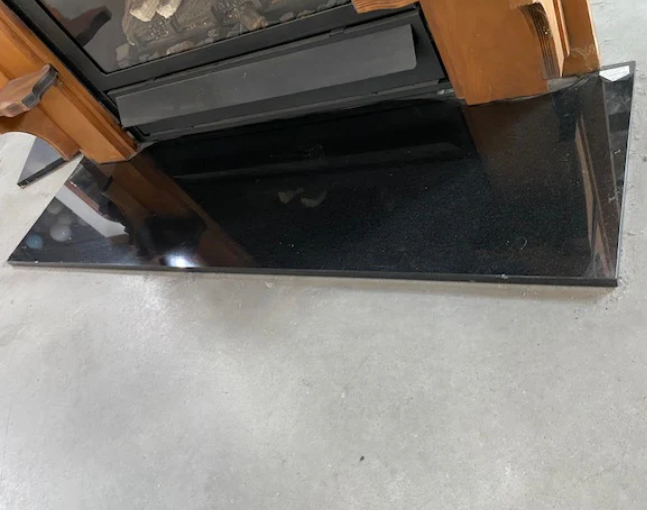 Polished black granite hearth slab with a high-gloss reflective finish installed beneath a fireplace