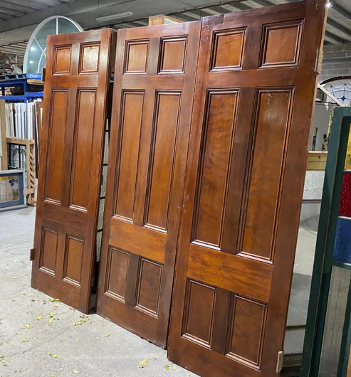 Set of three vintage 6-panel redwood room dividing doors with a rich timber finish, showcased at Chippendale Restorations second-hand door warehouse.