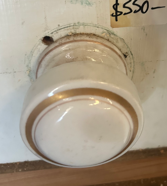 A close-up of an authentic, salvaged antique centre door knob made of solid brass with a deep, natural aged patina. The knob features a classic circular design with a stepped rose plate and visible wear that highlights its historical character and superior second-hand quality.