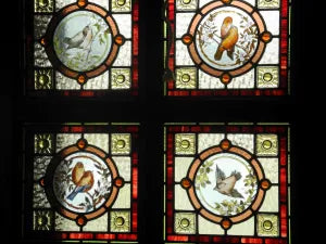 Four detailed hand-painted bird illustrations on stained glass panes inside a salvaged Victorian front door at Chippendale Restorations.