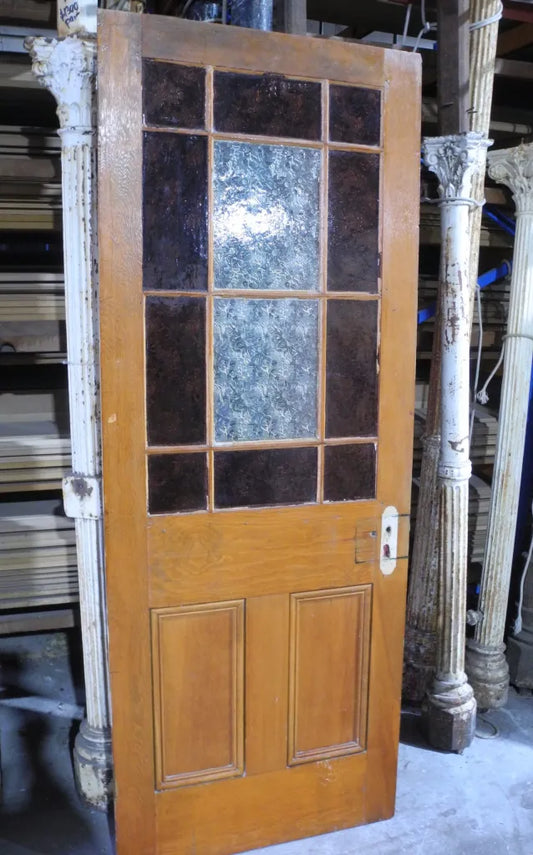 An original salvaged timber Federation gallery door painted white, showcasing an upper window with multi-lite red and amber glass framing a rare central pane of pressed flannel flower privacy glass at Chippendale Restorations.