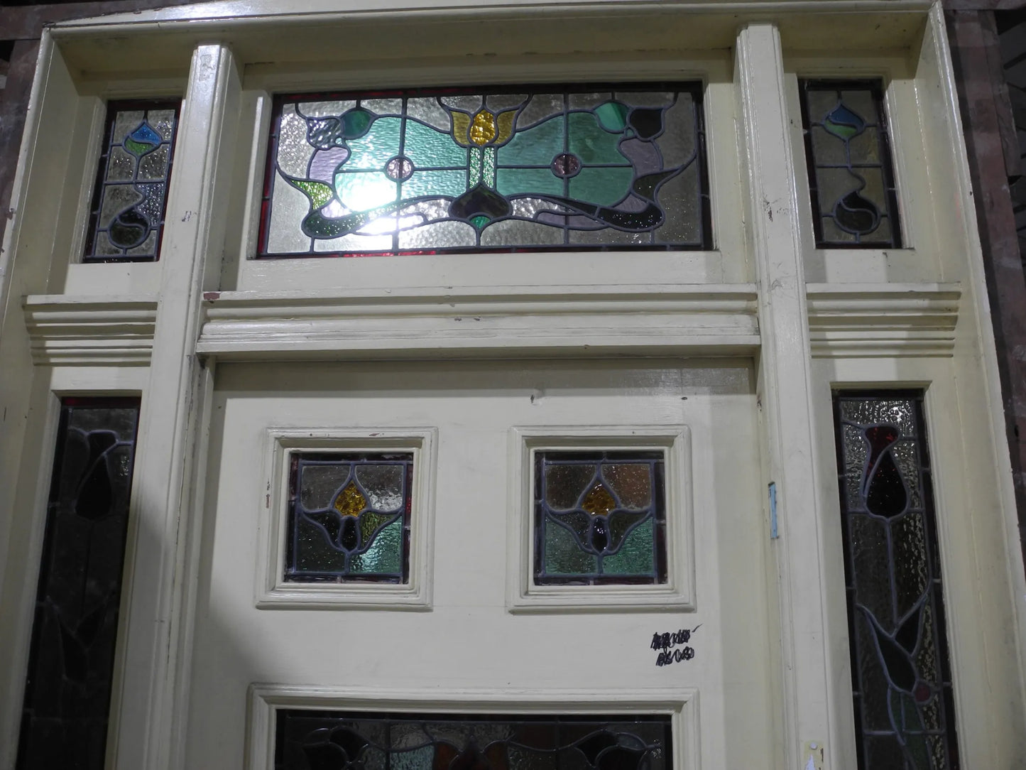 A spectacular original salvaged timber Federation entranceway door painted white, showcasing a large upper window with intricate textured privacy leadlight glass and vibrant red and amber stained glass accents on display at Chippendale Restorations.