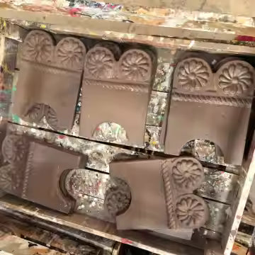 A single, curved, unglazed terracotta garden edge tile featuring an embossed design of two central daisy flowers above a twisted rope pattern, isolated on a white background.